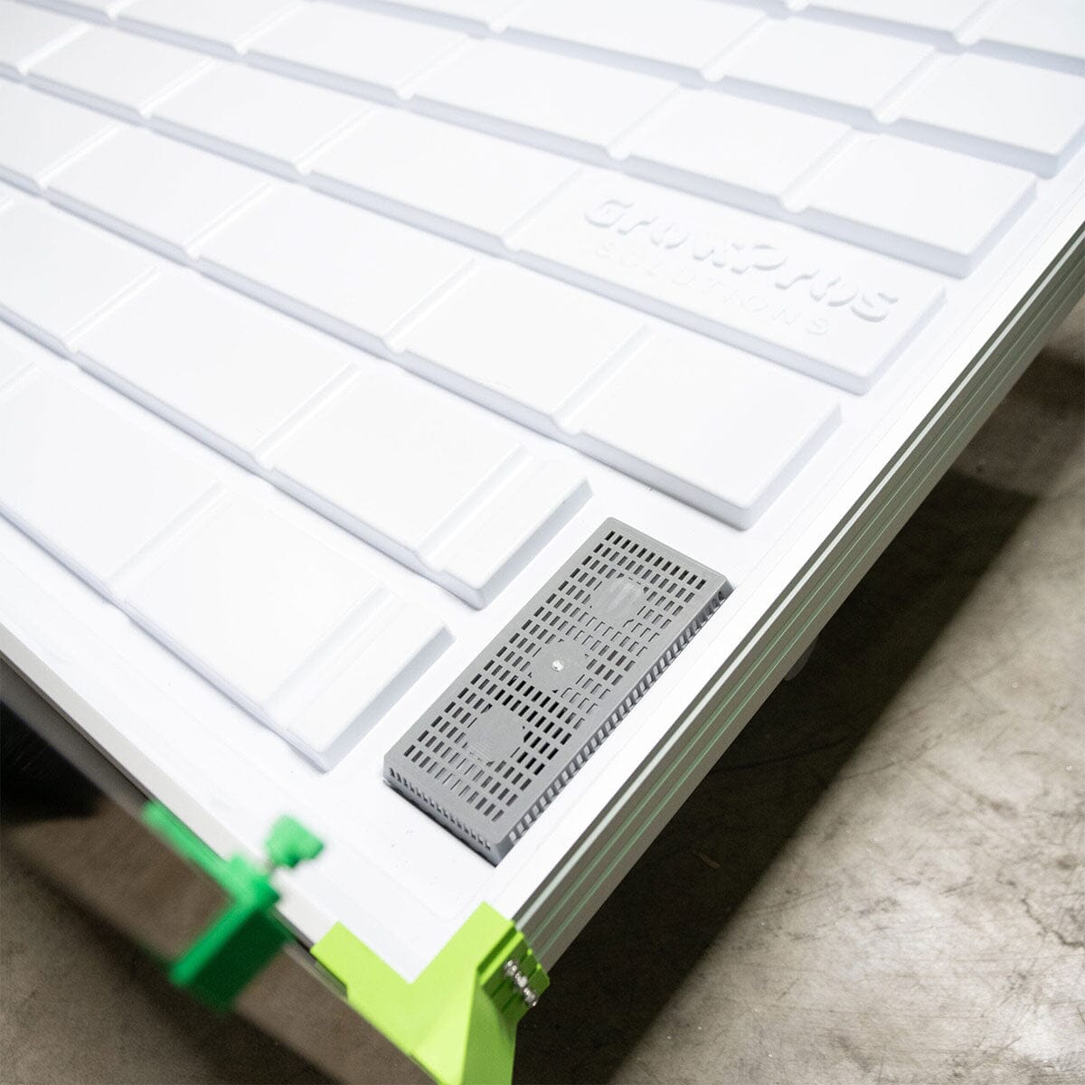 Grow tray corner with built-in drainage channel and branded surface, designed for efficient water flow.