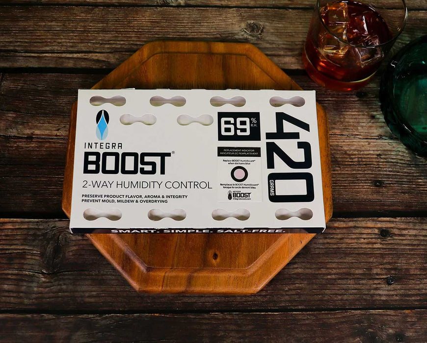 Integra BOOST 420g 69% RH humidity control pack on a wooden tray beside a drink, highlighting storage use context.