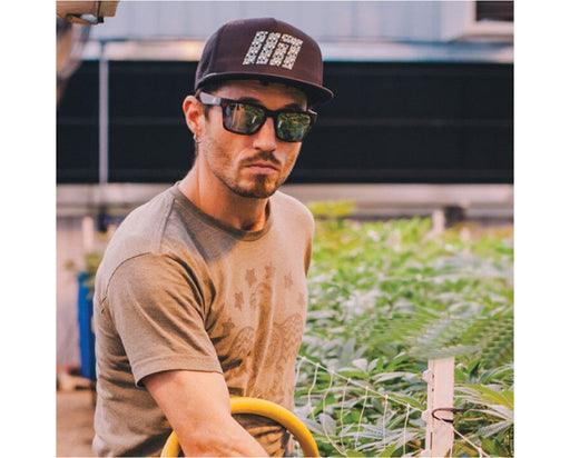 Man wearing Method Seven Evolution HPS+ glasses in a greenhouse, showcasing style and protection while working.