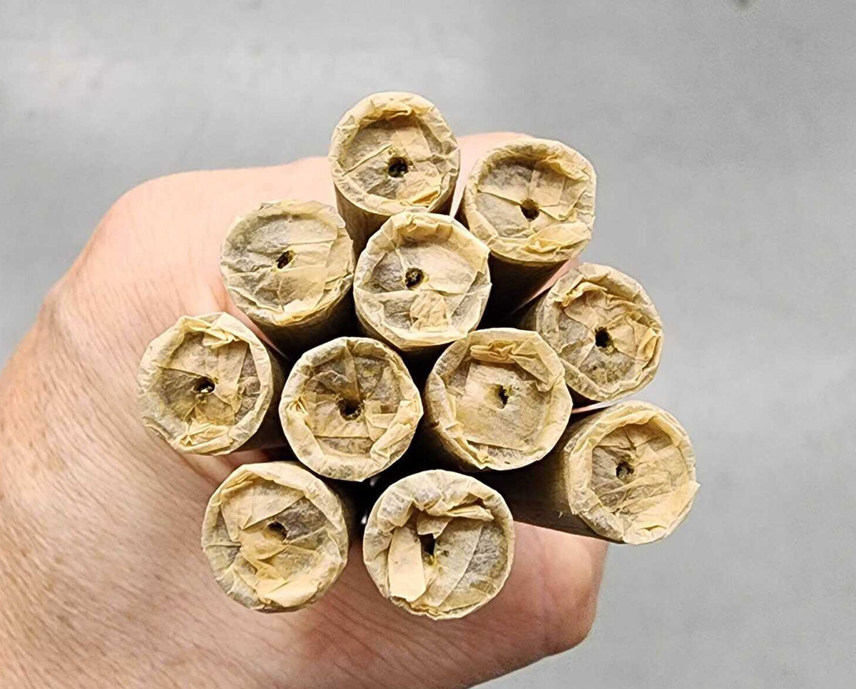 Close-up view of infused pre-roll tips held in hand, showing precise oil infusion and uniform paper twist from Astro Infuser.