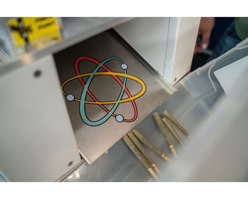 STM Atomic Closer logo chute dispensing freshly sealed pre-rolls into a plastic bin