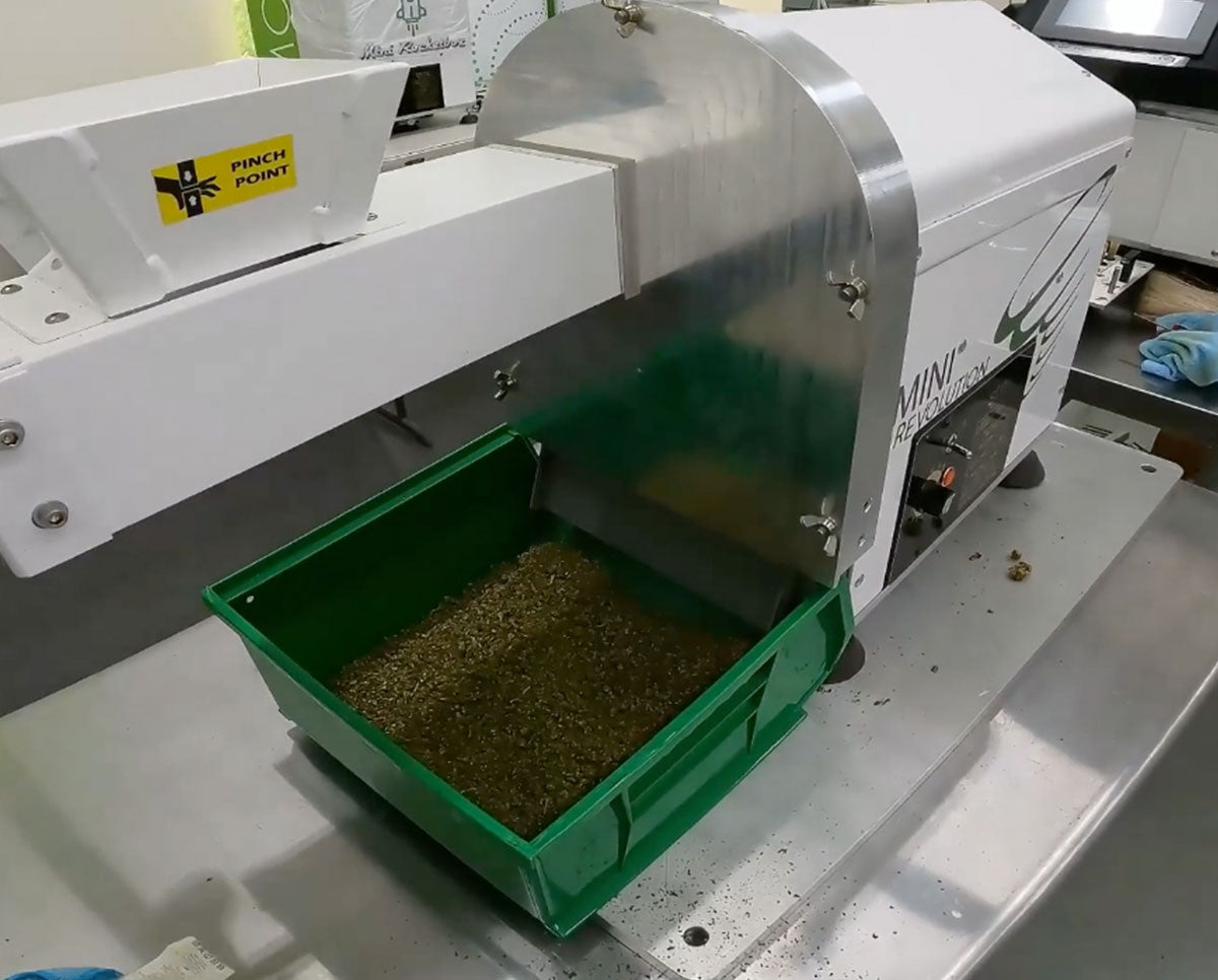 STM Mini-Revolution bud grinder processing flower into fine material, shown with green collection bin attached.