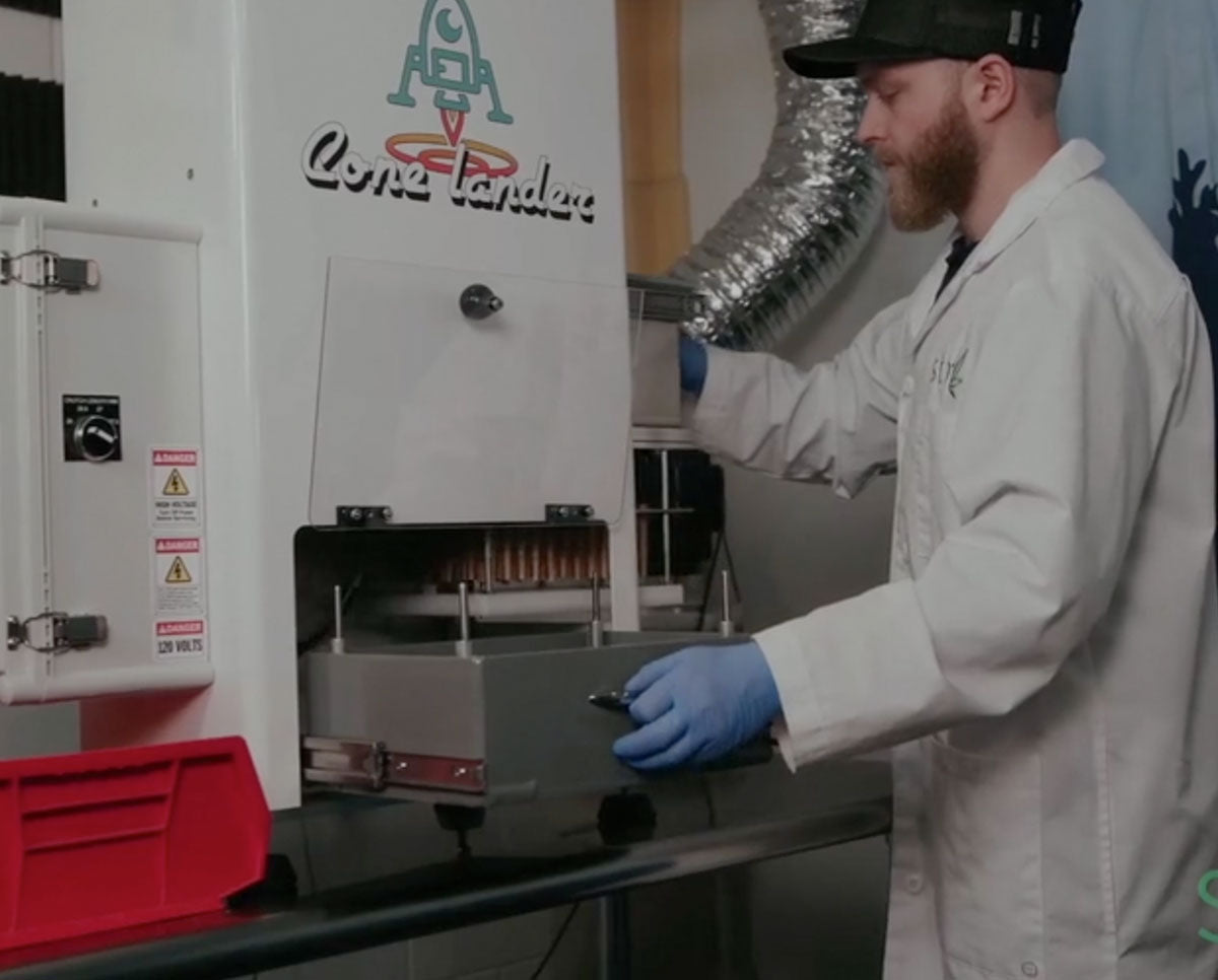 Technician operating STM Cone Lander pre-roll loader, automating the process of loading 72 cones for bud production.