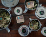 Several open and closed CVault Personal containers filled with flower and Boveda 62% RH humidity packs, arranged on a wooden surface to show different sizes.