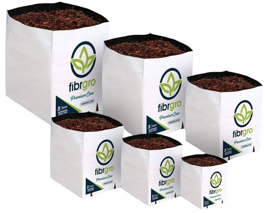 Lineup of six Fibrgro Premium Coco grow bags in varying sizes, all filled with a 40% coir chip and 60% fine coco pith mix and wrapped in white sleeves printed with Fibrgro branding.