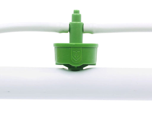 Close-up of green FloraFlex emitter connected to 16-17mm white irrigation tubing.