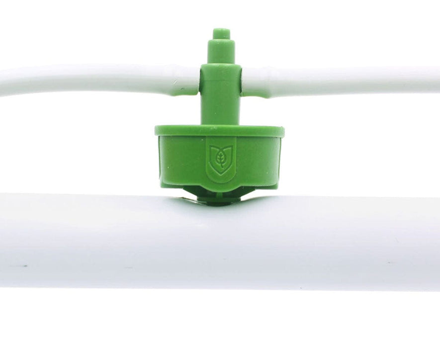 Close-up of green FloraFlex emitter connected to 16-17mm white irrigation tubing.