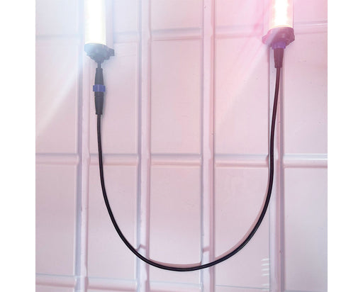 Two LED grow lights on a reflective surface with a GrowPros interconnect cable running between them.