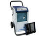 A large commercial-grade dehumidifier by Ideal-Air with the front filter panel removed, revealing the blue coil fins and internal components. The unit is mounted on wheels with a handle for mobility.