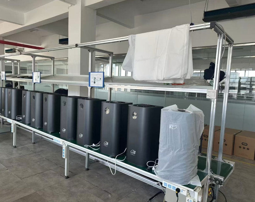 Production line with multiple Mammoth Clean Air 2nd Gen Air Sanitizers undergoing assembly and testing in a factory setting.