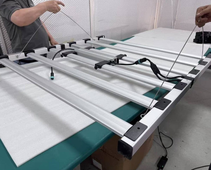 Technician assembling Mammoth Nova Sun Veg + Mom LED grow light with modular six bar folding frame.