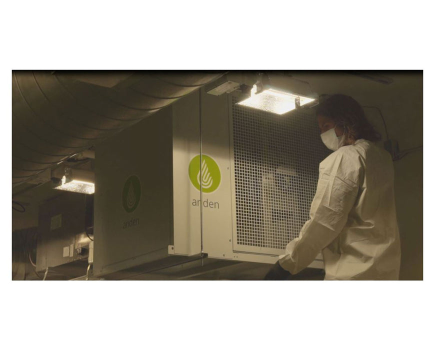 Person in lab coat and mask inspecting a mounted Anden dehumidifier in a controlled environment.