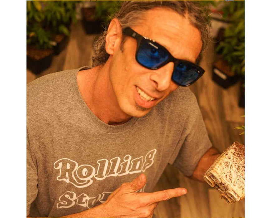 Man wearing Method Seven Coup HPS/Sun Transition glasses in an indoor grow room, holding a plant root ball.